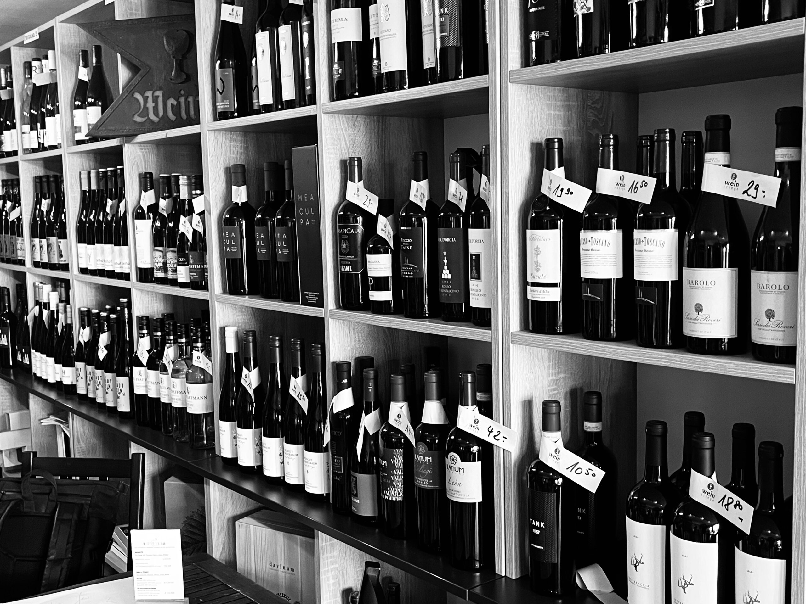 Gefülltes Weinregal mit Flaschen und handgeschriebenen Preisschildern