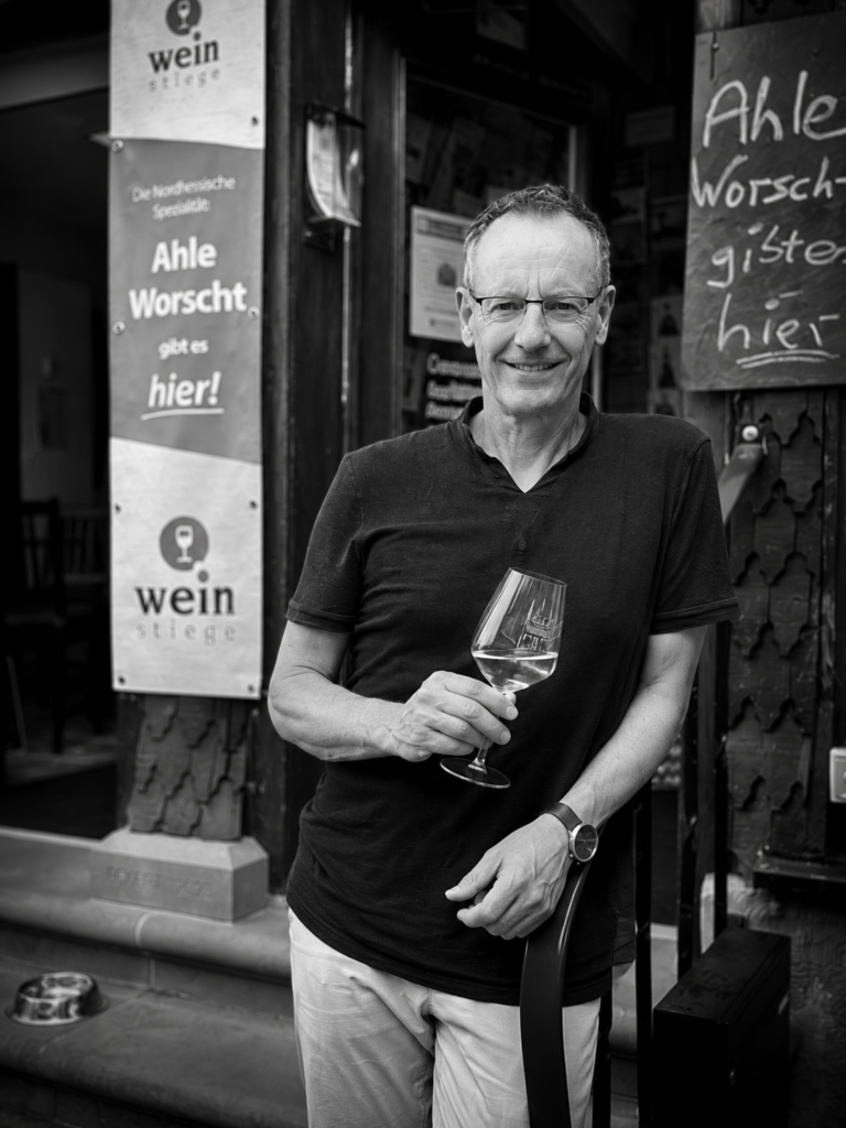 Andreas Terstiege mit Weinglas vor dem Eingang der WEINSTIEGE